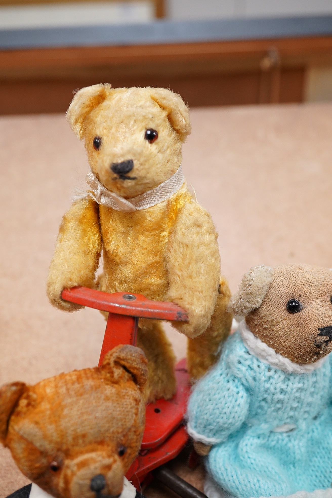 A mechanical bear on a bike in good working condition, a red Schuco bear, faded condition, c.1920, 13cm, a tumbling Schuco bear, working, 10cm, c.1920, a green Schuco bear missing one ear, c.1920, 7cm. high, together wit